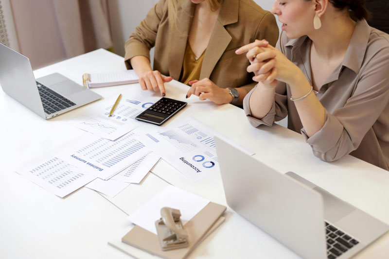 Une comptable et sa cliente faisant la comptabilité avec deux laptop ouverts sur la table