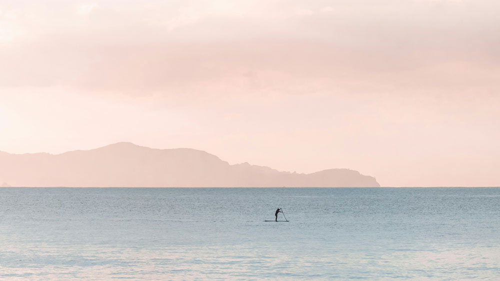 Une personne naviguant tranquillement sur une mer calme avec des collines en arrière-plan à peine visible | KYTE : Programme de facturation de Clearfacts